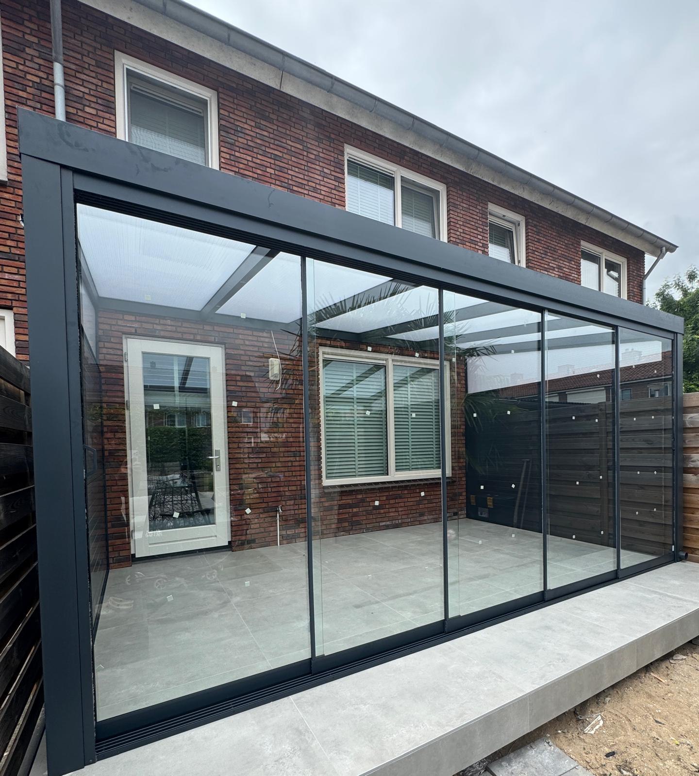 Veranda tegen bakstenen gevel, aluminium schuifwanden, helder terras