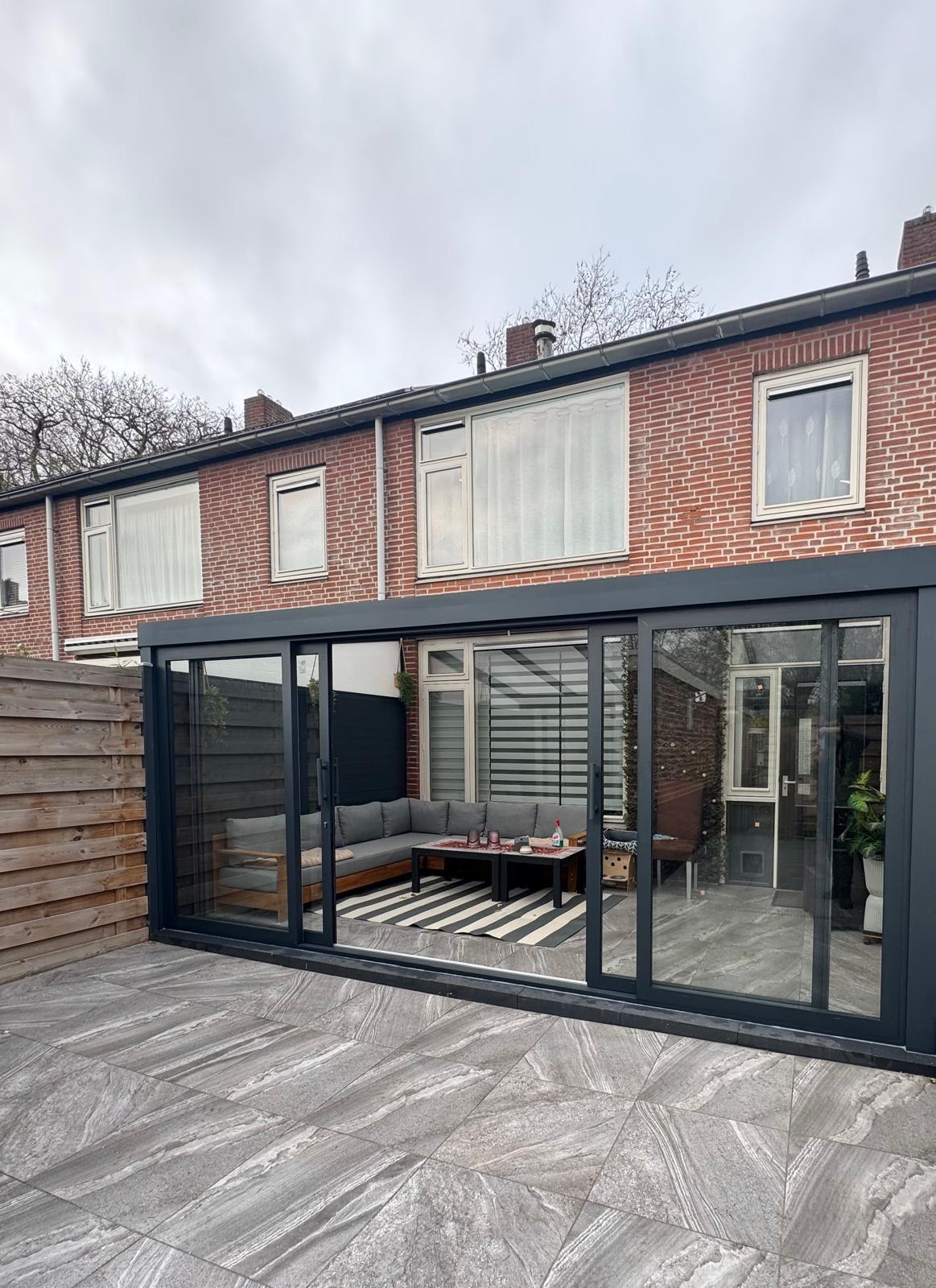 Ingerichte veranda als loungeruimte met zitbank en salontafel